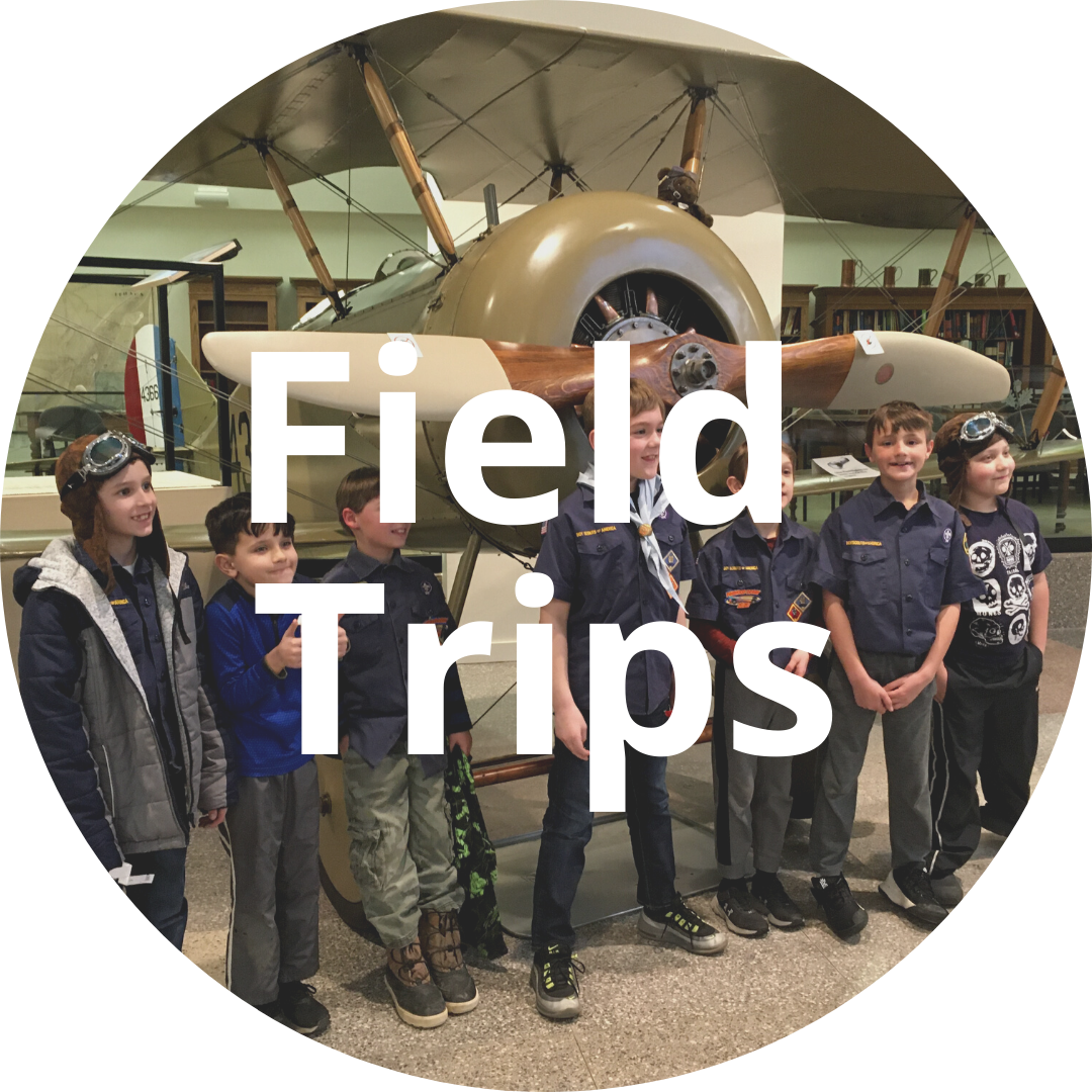 Circular area with the text "Field trips" overlayed on an image of students in front of the Tommy plane.