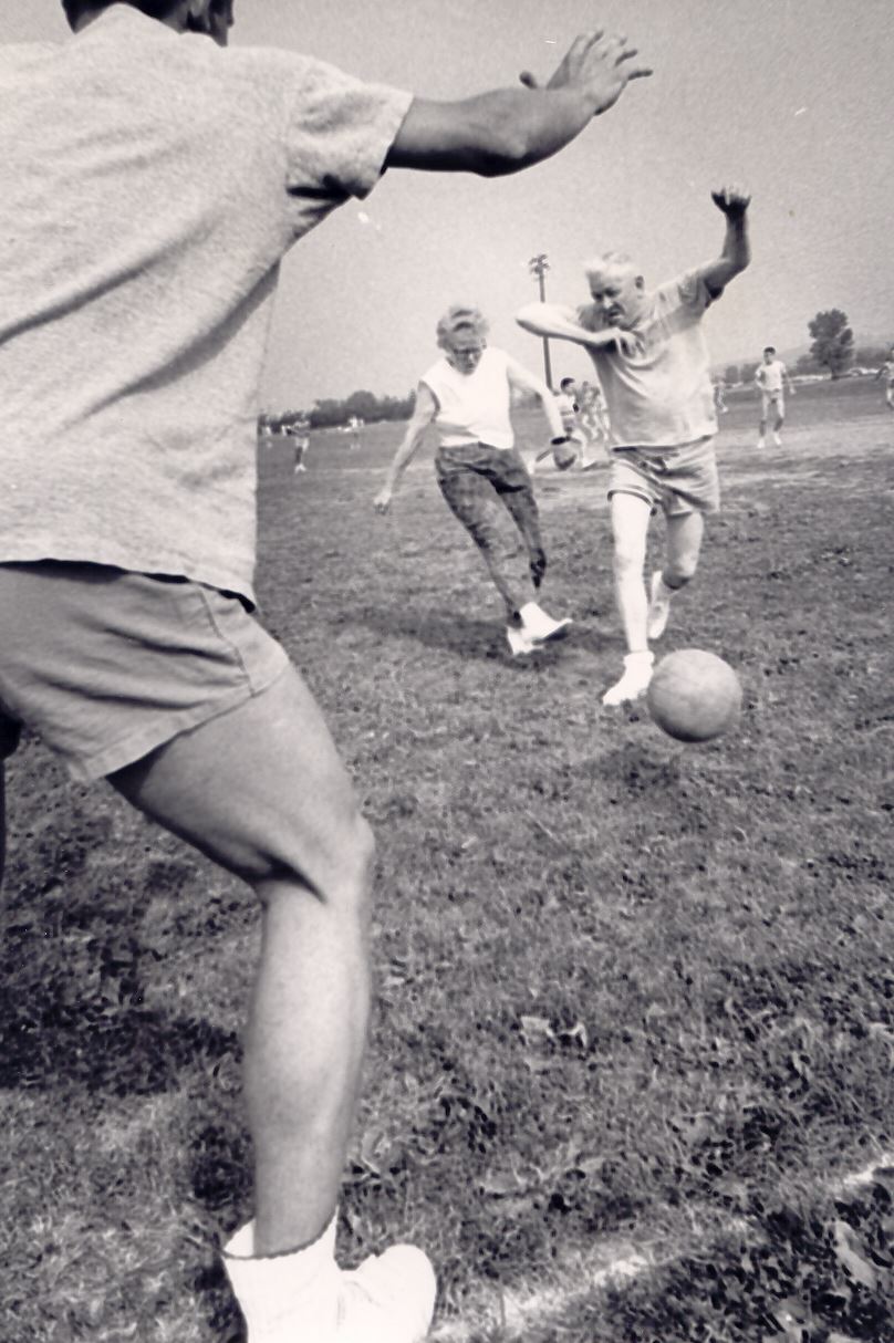 Black and white image of three people playing soccer