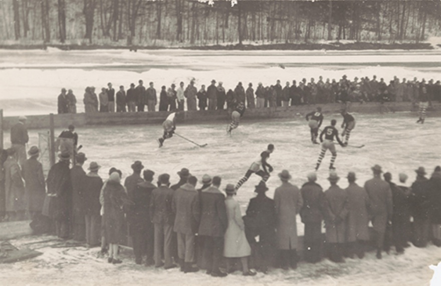 Circular text area that reads ”Ithaca Heritage” overlaid over a black and white image of a hockey game on beebe lake.